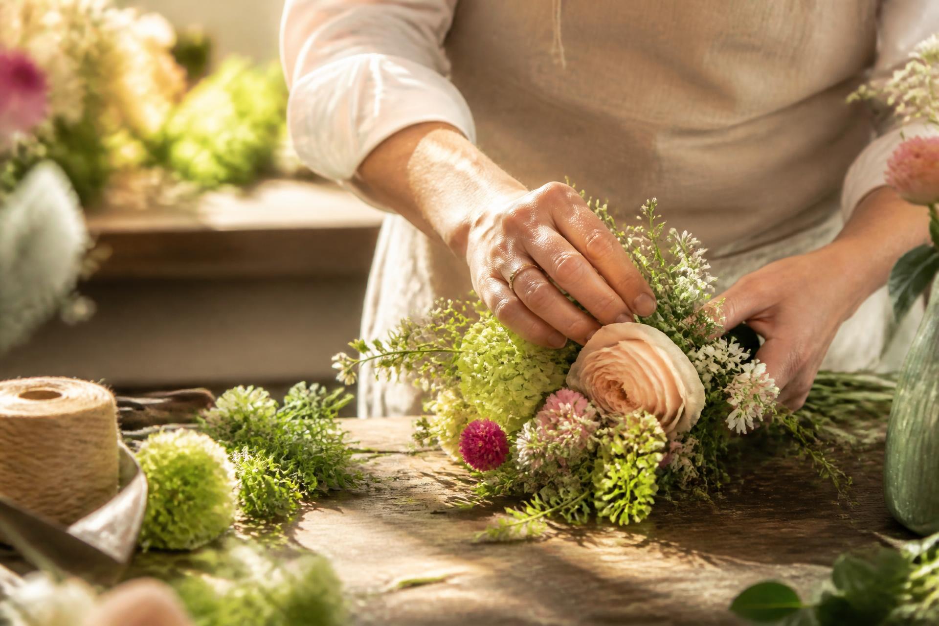 Mains manipulant délicatement des fleurs dans un atelier lumineux